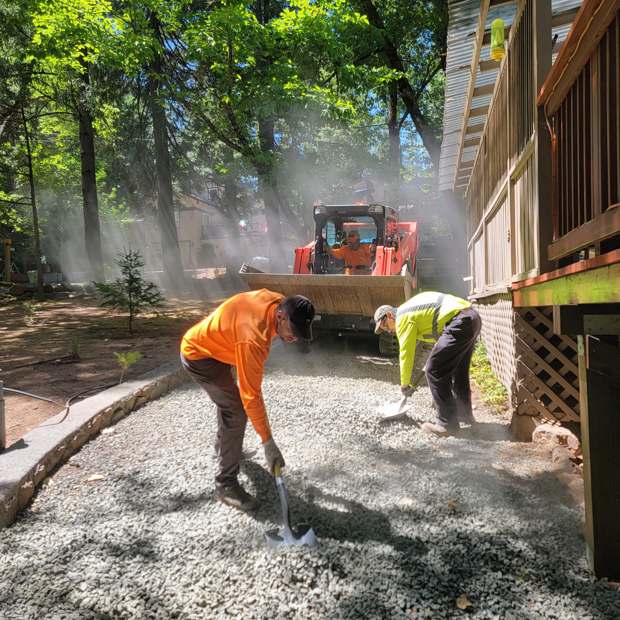 Two R2 crew members spreading gravel on a cleared path