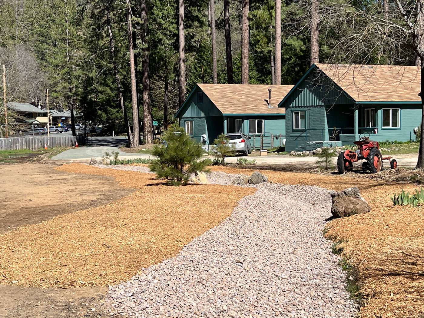 A cleared yard in front of a green cabin with a new gravel path