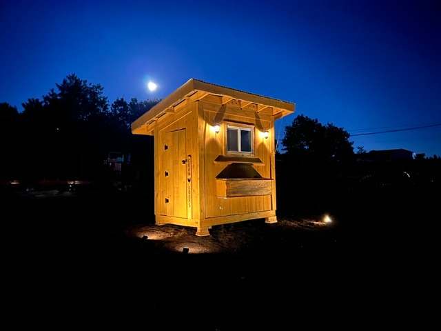 A small shed built from milled lumber, lit up at night